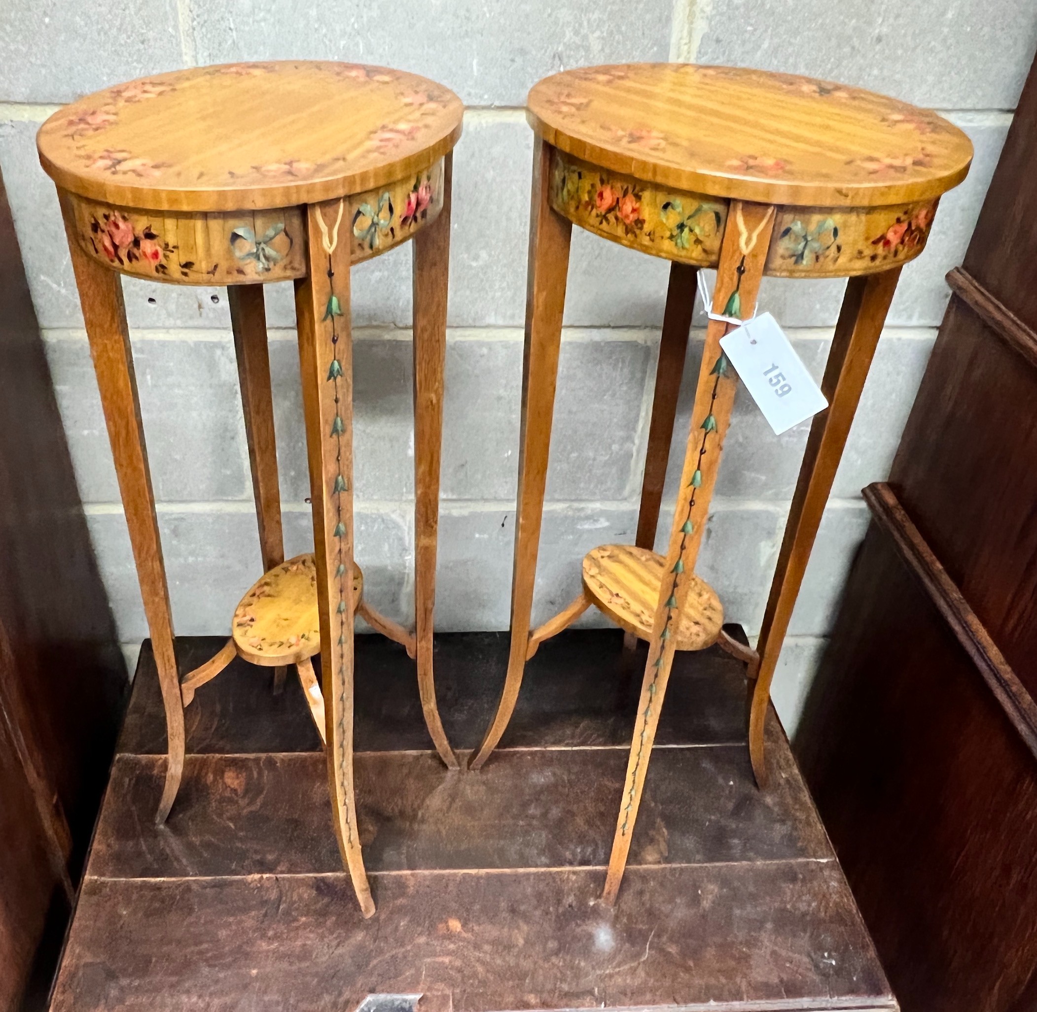A pair of oval Sheraton style painted satinwood two tier plant stands, width 32cm, depth 26cm, height 71cm